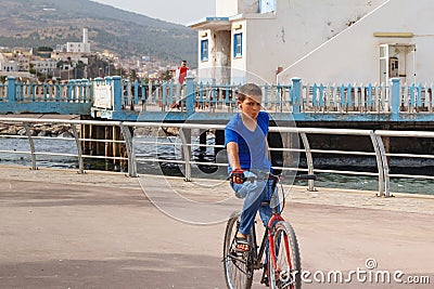 NADOR, MOROCCO - MAY 22, 2017: Arabian boy with an unkind suspicious look on a bicycle rides along the promenade near Mar Chica Editorial Stock Photo