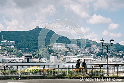 Nagasaki, Kyushu, Japan, East Asia - Students going home after school in a background of beautiful landscape with sea and mountain Editorial Stock Photo