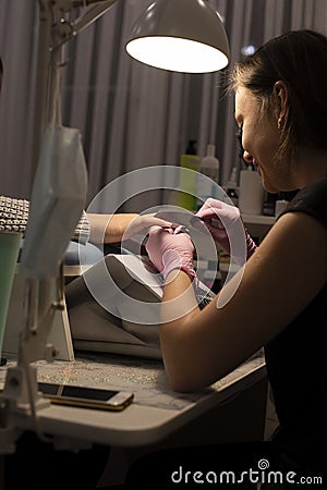 In the nail salon client manicurist in gloves handles nails with nail files Stock Photo