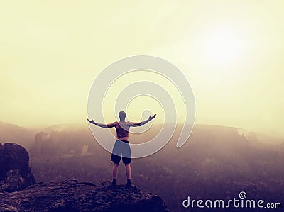 Naked hiker stand on the corner of sandstone rock in rock empires park and watching over the misty and foggy morning valley to Sun Stock Photo