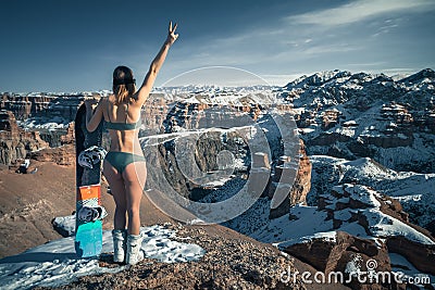 Naked snowboarder girl with snowboard and ski glasses at unusual amazing the Charyn Canyon Stock Photo