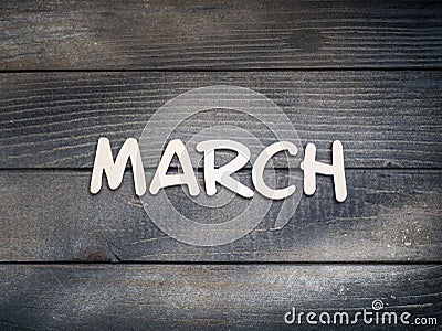 The name of the month is composed of light wooden letters on dark wood. The month of March. Stock Photo