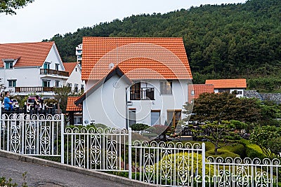 Namhae,South Korea-November 2020: Germany style red roof and white wall house building with mountain view with white fence at Editorial Stock Photo