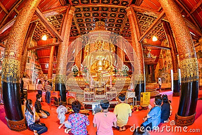 Buddhist tourists worshiping golden Buddha image Editorial Stock Photo