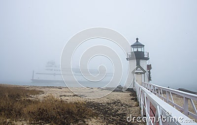 The Nantucket Island ferry boat sails past the Brant Point Lighthouse in fog Stock Photo