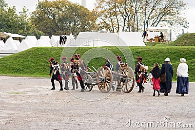 Napoleonic soldiers and their women are marching to a military camp. Napoleonic base with white tents Editorial Stock Photo