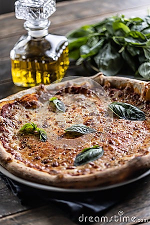 Napoli pizza with tomato sauce and mozzarella, fresh basil and a carafe of olive oil in the background Stock Photo