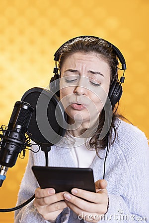 Narrator glowers, portraying character, recording audiobook, studio background Stock Photo
