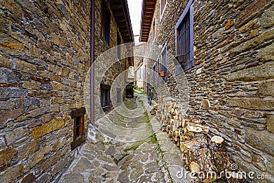 Narrow alley between old stone houses, a bicycle and firewood logs for the winter. La Hiruela Madrid Stock Photo