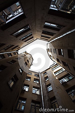 Narrow buildings well in Saint-Petersburg with the sky above the roofs. Below view. Stock Photo