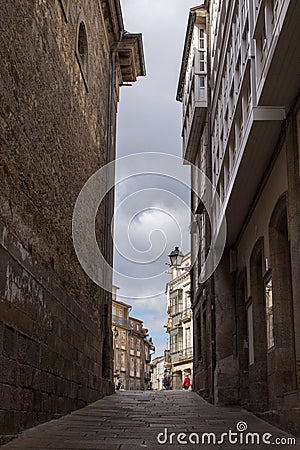 Narrow empty street in Santiago de Compostela, Spain. Road between ancient stone buildings. Medieval architecture. Travel concept. Stock Photo