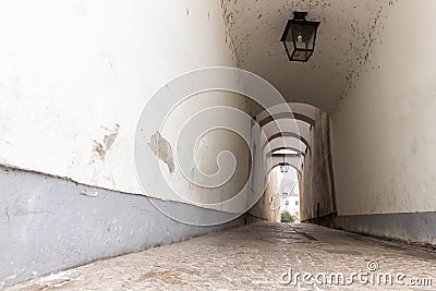 Narrow inner paved stone urban street road passage in old european city. Vintage dark alley with lamp lantern and grey Stock Photo