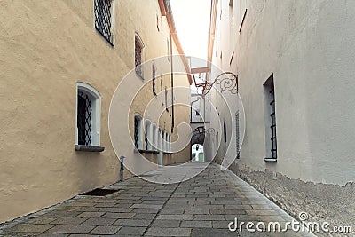 Narrow inner paved stone urban street road passage in old european city. Vintage dark alley with lamp lantern and grey Stock Photo