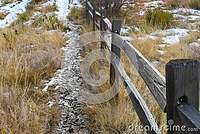 Narrow muddy trail by the side of an old fence. Stock Photo