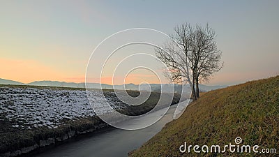 Narrow river with soft water flows in winter towards twilight horizon Stock Photo
