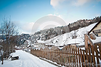 Narrow road covered by snow at countryside. Winter landscape with snowed trees, road and wooden fence. Cold winter day at village Stock Photo