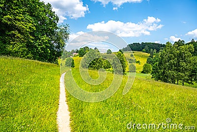 Narrow rural pathway in green hilly landscape Stock Photo