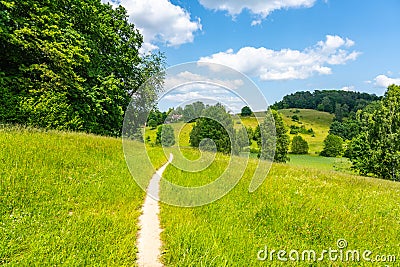 Narrow rural pathway in green hilly landscape Stock Photo