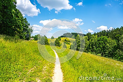 Narrow rural pathway in green hilly landscape Stock Photo
