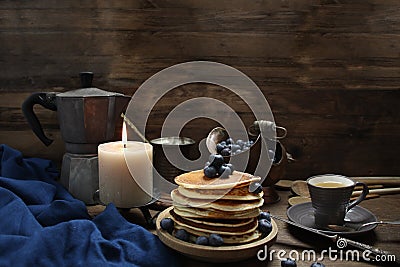 National dish pancakes, pancakes, pita with blueberries, linen napkin, poured with honey, candle burns, a cup of tea, an old mocha Stock Photo