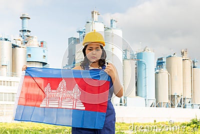 National flag of Cambodia in the hands of girl in overalls against background of modern metallurgical plant Stock Photo