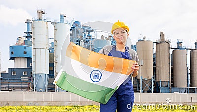 National flag of India in the hands of girl in overalls against background of modern metallurgical plant Stock Photo
