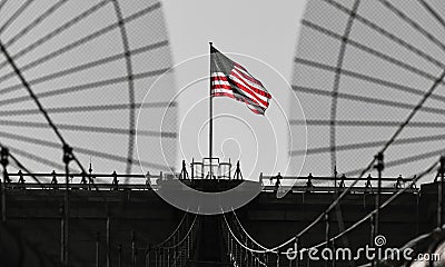 The national flag of United States of America winding on top of Brooklyn Bridge landmark from Manhattan. Editorial Stock Photo