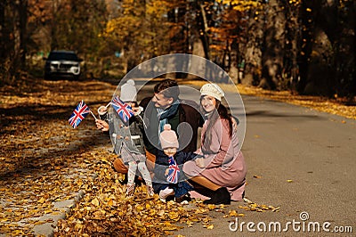 National holiday of United Kingdom. Family with british flags in autumn park. Britishness celebrating UK. Two kids Stock Photo