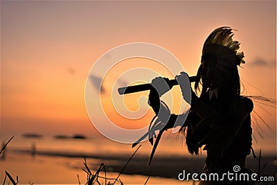 A Native American Indian plays music on a bamboo flute. Stock Photo