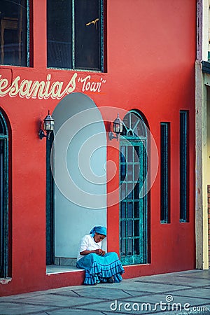 Native lonely Indigenous lady in traditional colorful dress with a beautiful house, in Mexico, America Editorial Stock Photo