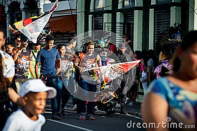 Native people carry group flags in hands walking by city street at dominican carnival Editorial Stock Photo