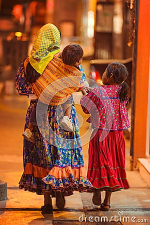 Native poor Indigenous lady and children in traditional colorful dress in city at night, Mexico, America Editorial Stock Photo