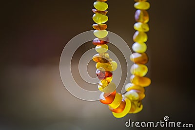 Natural amber beads shining on sun close up. Handmade souvenir of real gems on a dark background, selective focus Stock Photo