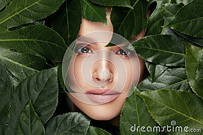 Natural Beauty. Beautiful Woman Face In Green Leaves. Stock Photo