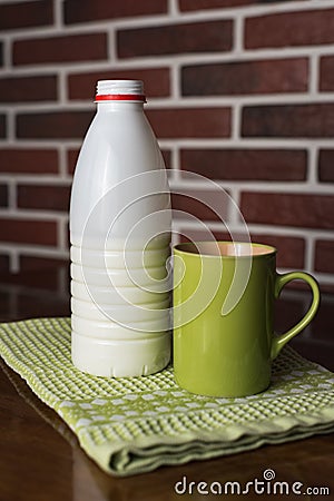 Natural bio milk product. Half bottle of natural milk, kefir and green mug, on a beautiful light green color napkin, wooden table Stock Photo