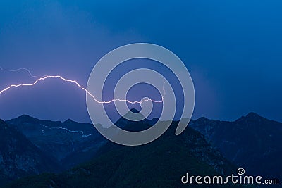 Bolt lightning over mountain peak silhouette with dark blue sky Stock Photo