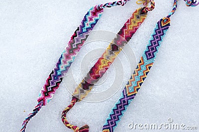 Natural bracelets of friendship in a row, colorful woven friendship bracelets, snow background, rainbow colors, checkered pattern Stock Photo