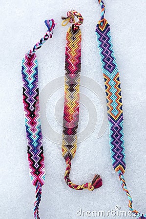 Natural bracelets of friendship in a row, colorful woven friendship bracelets, snow background, rainbow colors, checkered pattern Stock Photo