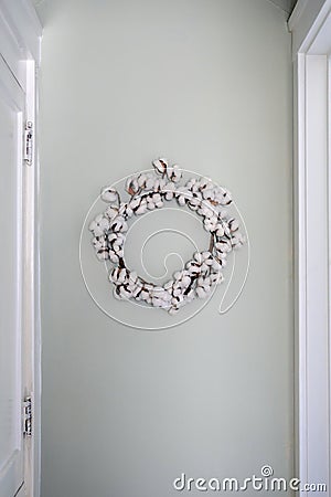 Natural cotton wreath hanging on light aqua wall Stock Photo