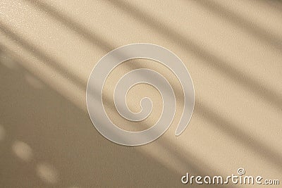 Natural diagonal shadow from a window on a textured, rough, glossy surface, toned in beige. Stock Photo