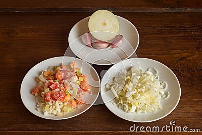 Natural food ingredients and vegetables on white plates on a chestnut wooden table. Stock Photo