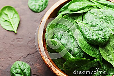 Natural fresh baby spinach leaves in wooden bowl on vintage stone table. Organic healthy food. Stock Photo