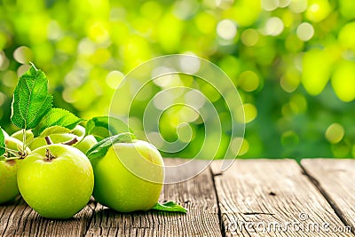 Natural green apples with leaves on empty wooden table for montage against blurred summer orchard background Stock Photo