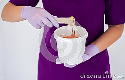 Women beautician holds jar wax of paste for sugar depilation shugaring, white background Stock Photo