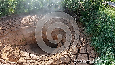 A natural hot spring is a mud pot. There are deep cracks on the clay edges. Stock Photo