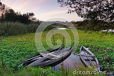 Natural landscape with boats in the water at sunset. Amazing lake with small artisanal fishing boats. Sunrise light reflected in w Stock Photo