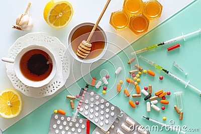 Natural medicine, tea, honey, lemon and garlic against tablets of syringes and other medications, top view background in two color Stock Photo