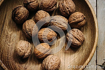 Natural nuts and in a stylish unique rustic bowl on a wooden b Stock Photo