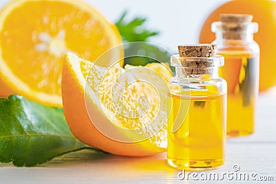 Natural orange essential oil in bottle and cut oranges fruit on white wooden table Stock Photo