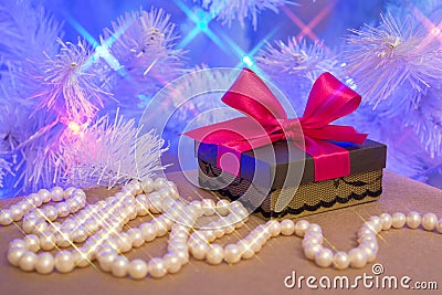 Natural pearl garland and a gift wrapped present with red bow Stock Photo